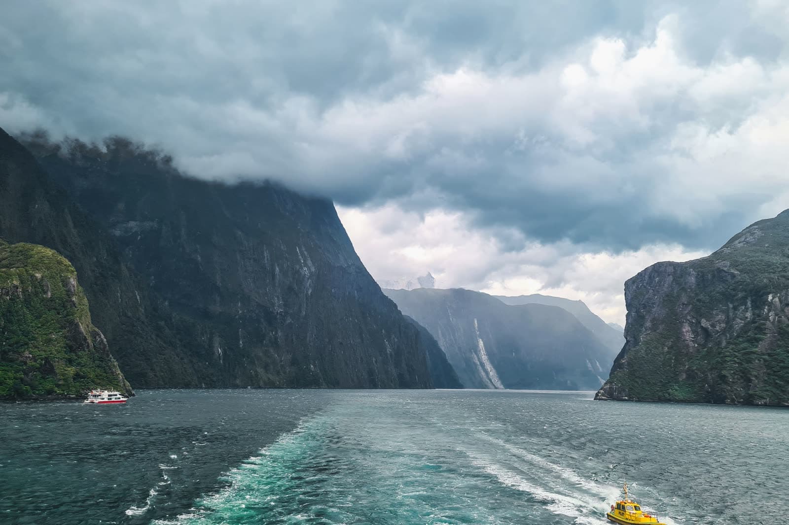 The sheer walls of Milford Sound closing in behind a boat's wake.