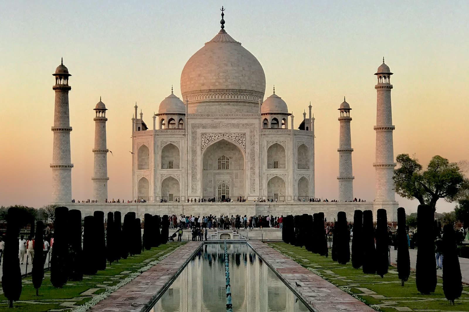 The Taj Mahal at dawn, mirrored in the long reflecting pool of its formal garden.