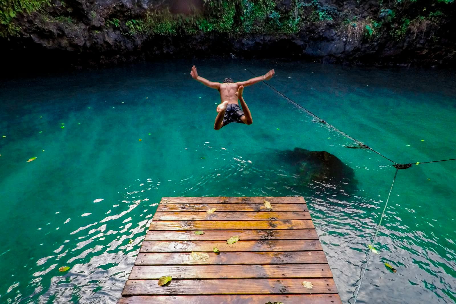 A swimmer leaping into the To Sua Ocean Trench from its wooden platform.