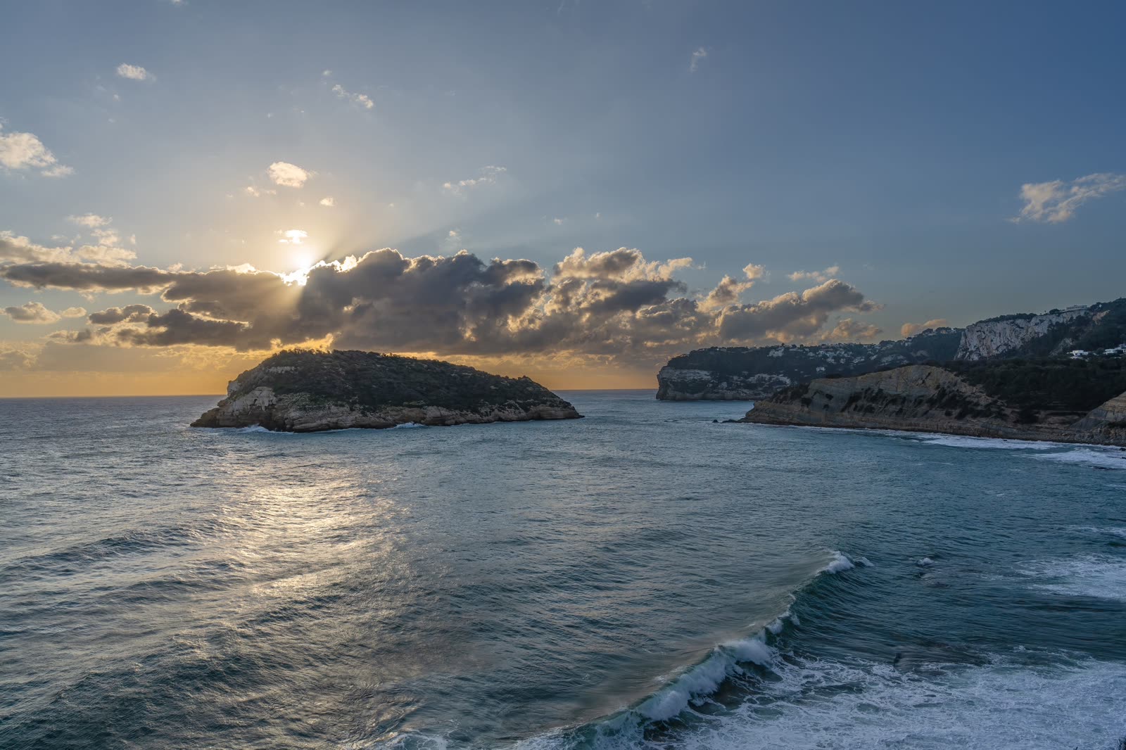 The sun setting over the Aegean behind a distant island.