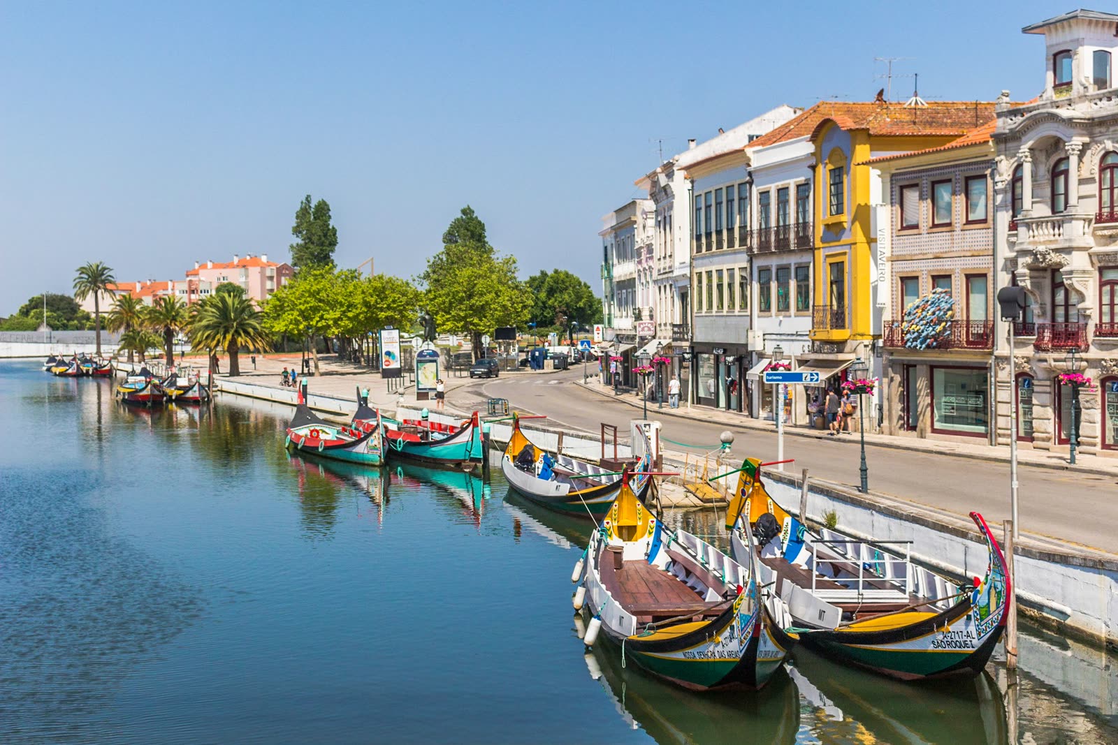 Painted moliceiro boats moored along a canal, with Art Nouveau facades behind.
