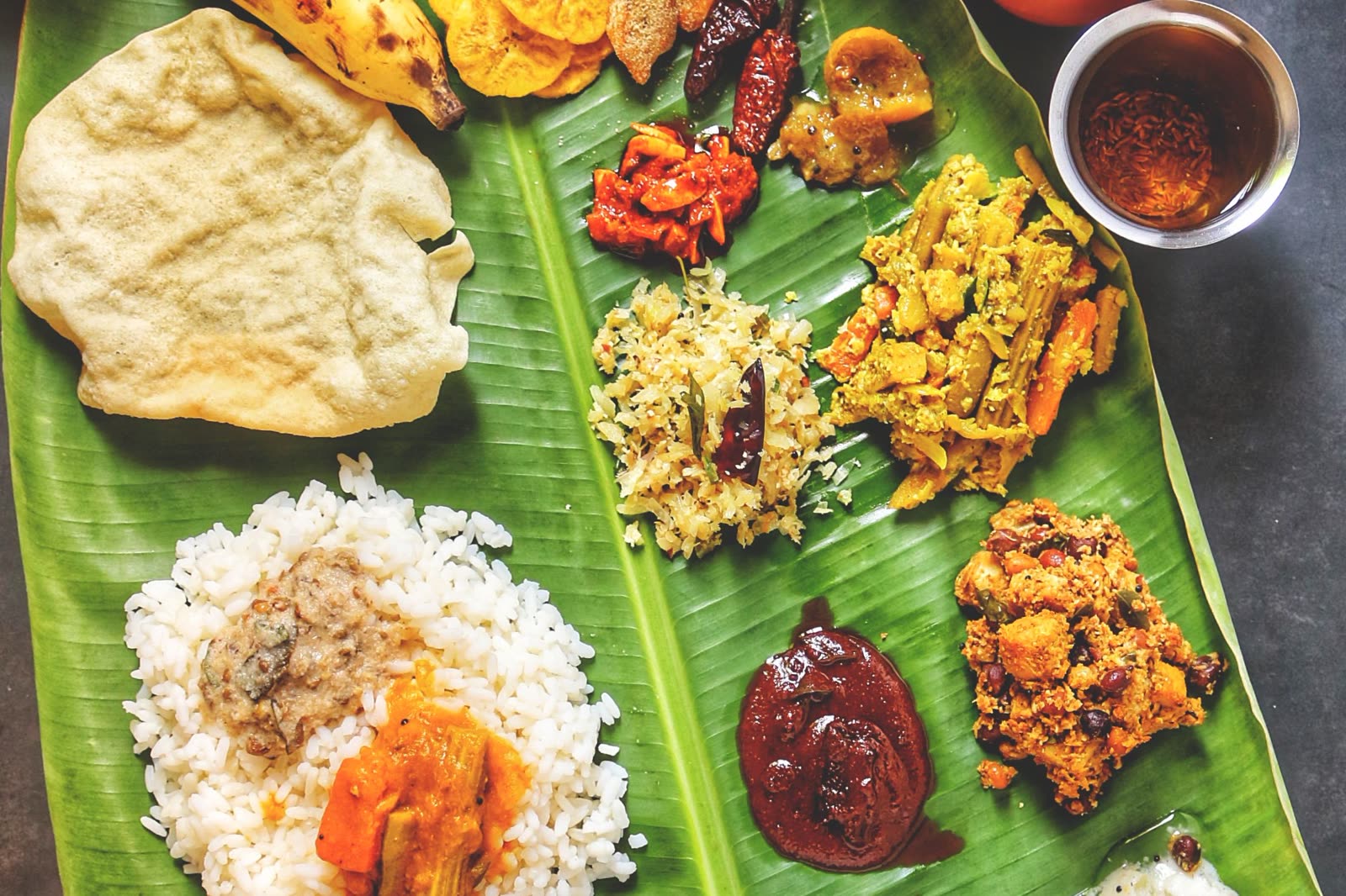 A South Indian thali served on a banana leaf, with rice, curries, pickles and sweets.
