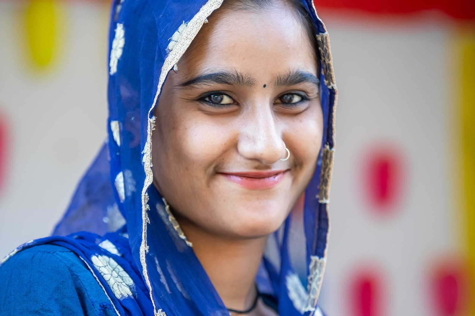 A young woman in a blue sari and embroidered headscarf.