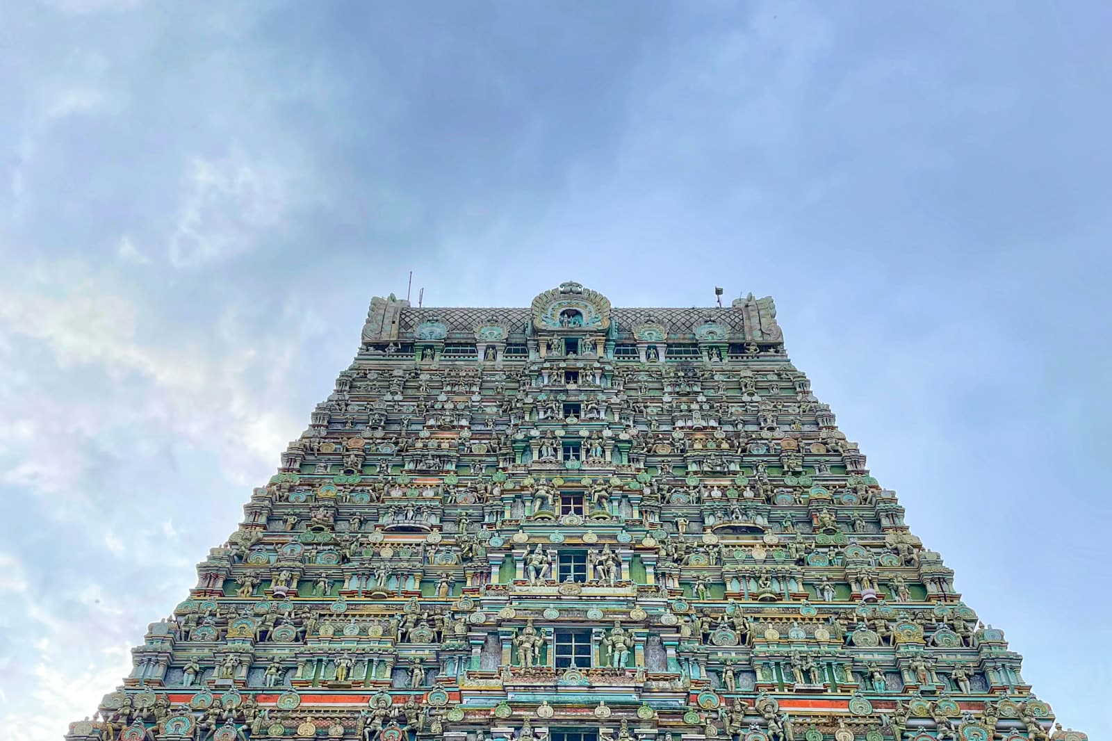 A towering Dravidian gopuram covered in painted sculpture, rising against the sky.