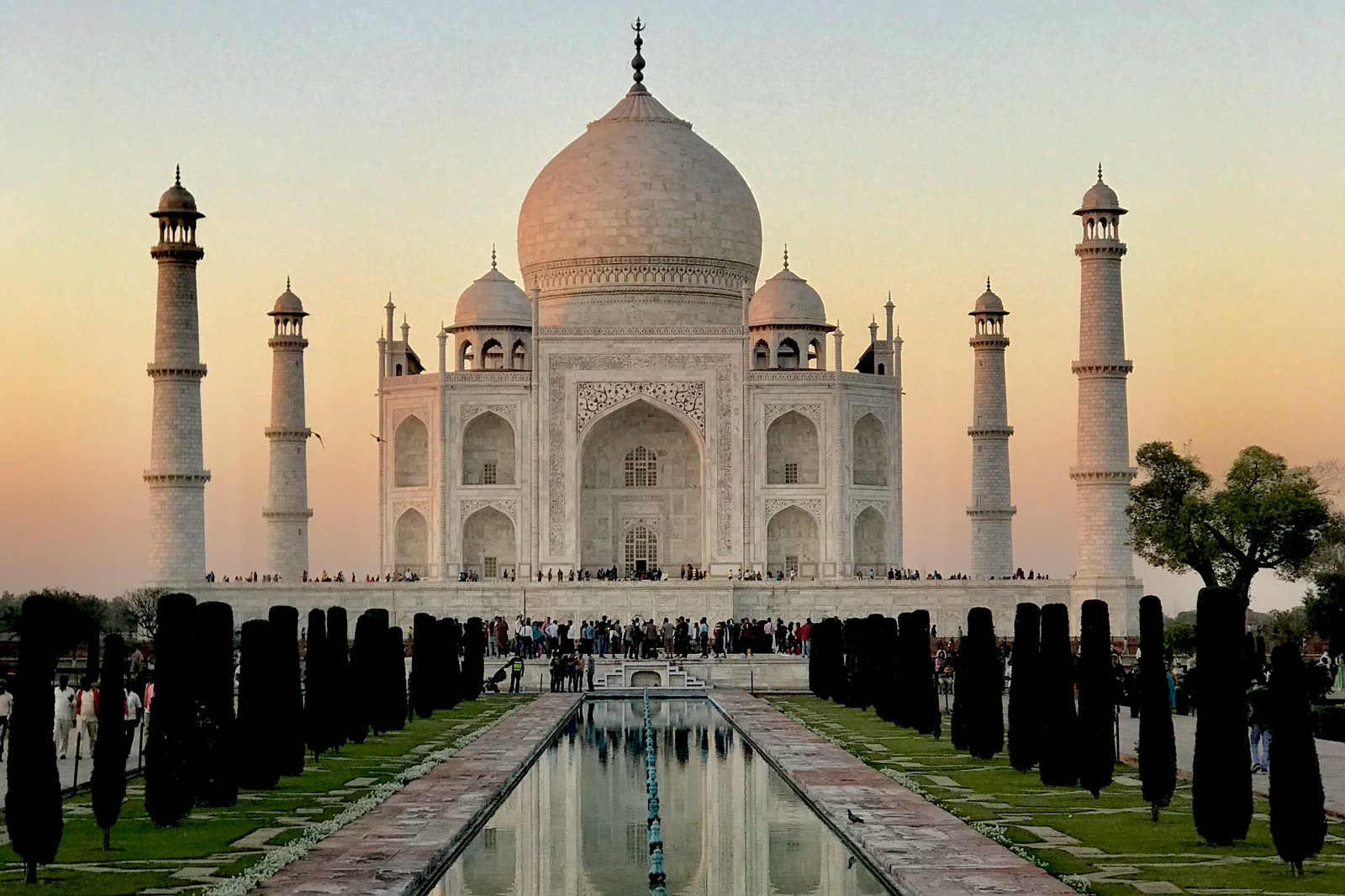 The Taj Mahal at dawn, mirrored in the long reflecting pool of its formal garden.