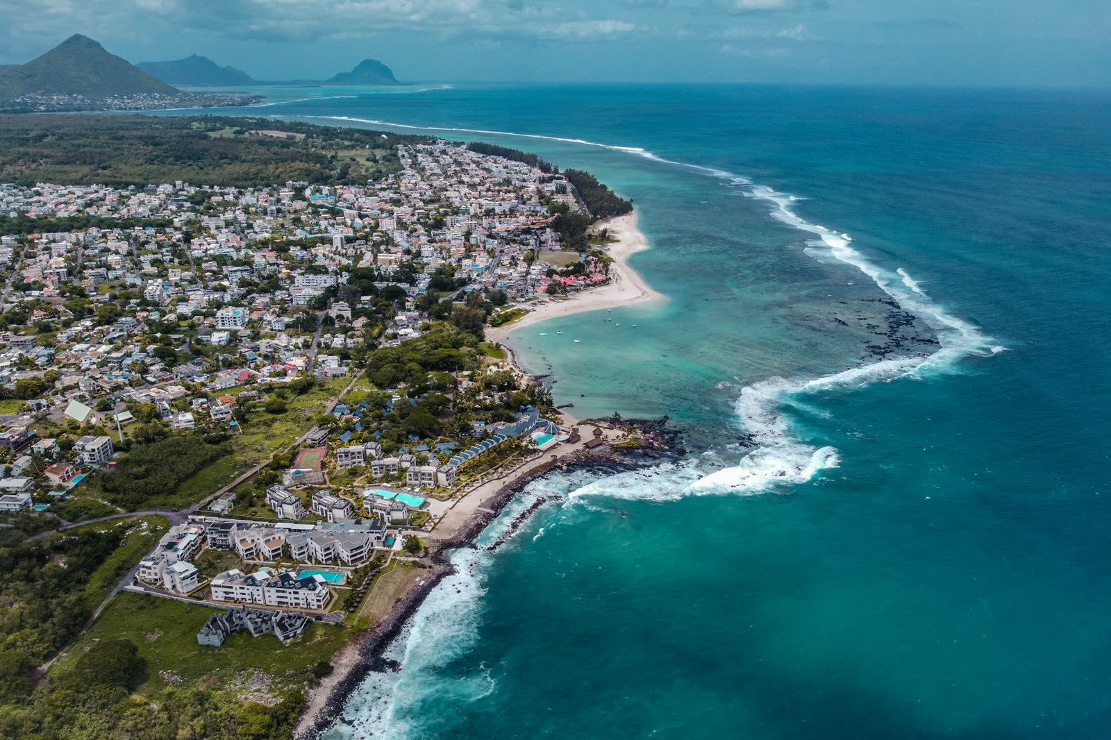 An aerial view of the Mauritian coast, its reef break offshore and mountains inland.
