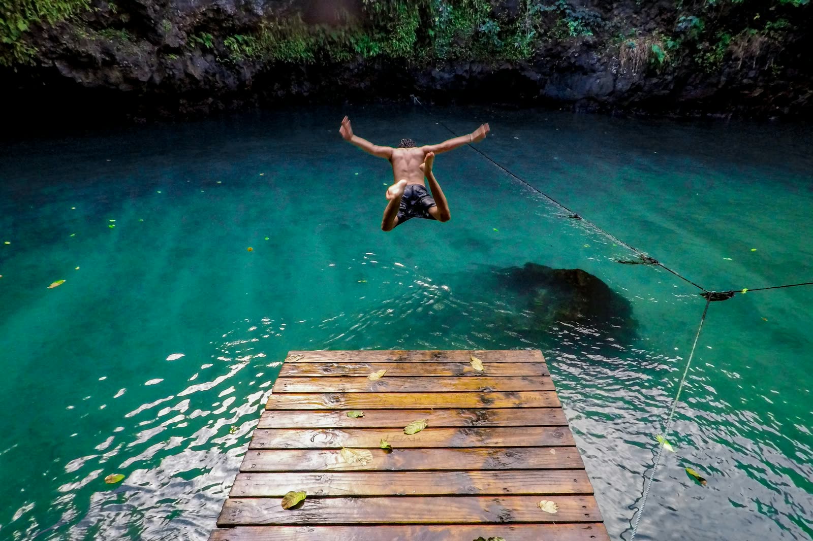 A swimmer leaping into the To Sua Ocean Trench from its wooden platform.