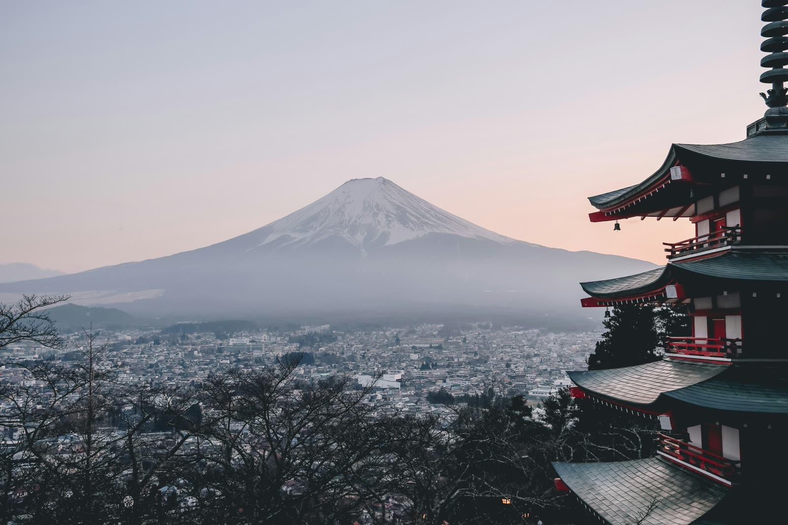 Mount Fuji at dawn seen past the tiers of a pagoda.