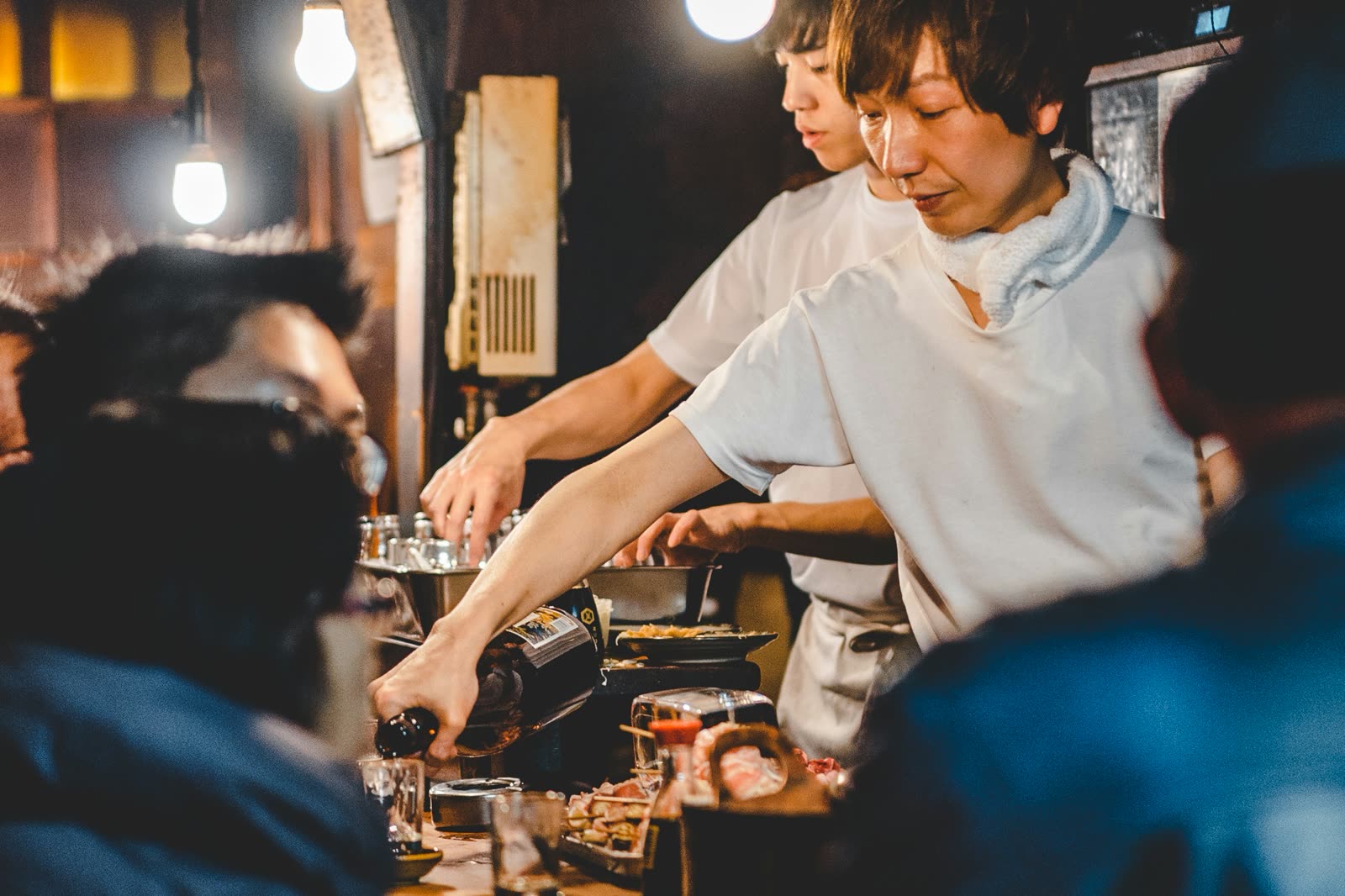 Cooks working the counter of a busy izakaya.
