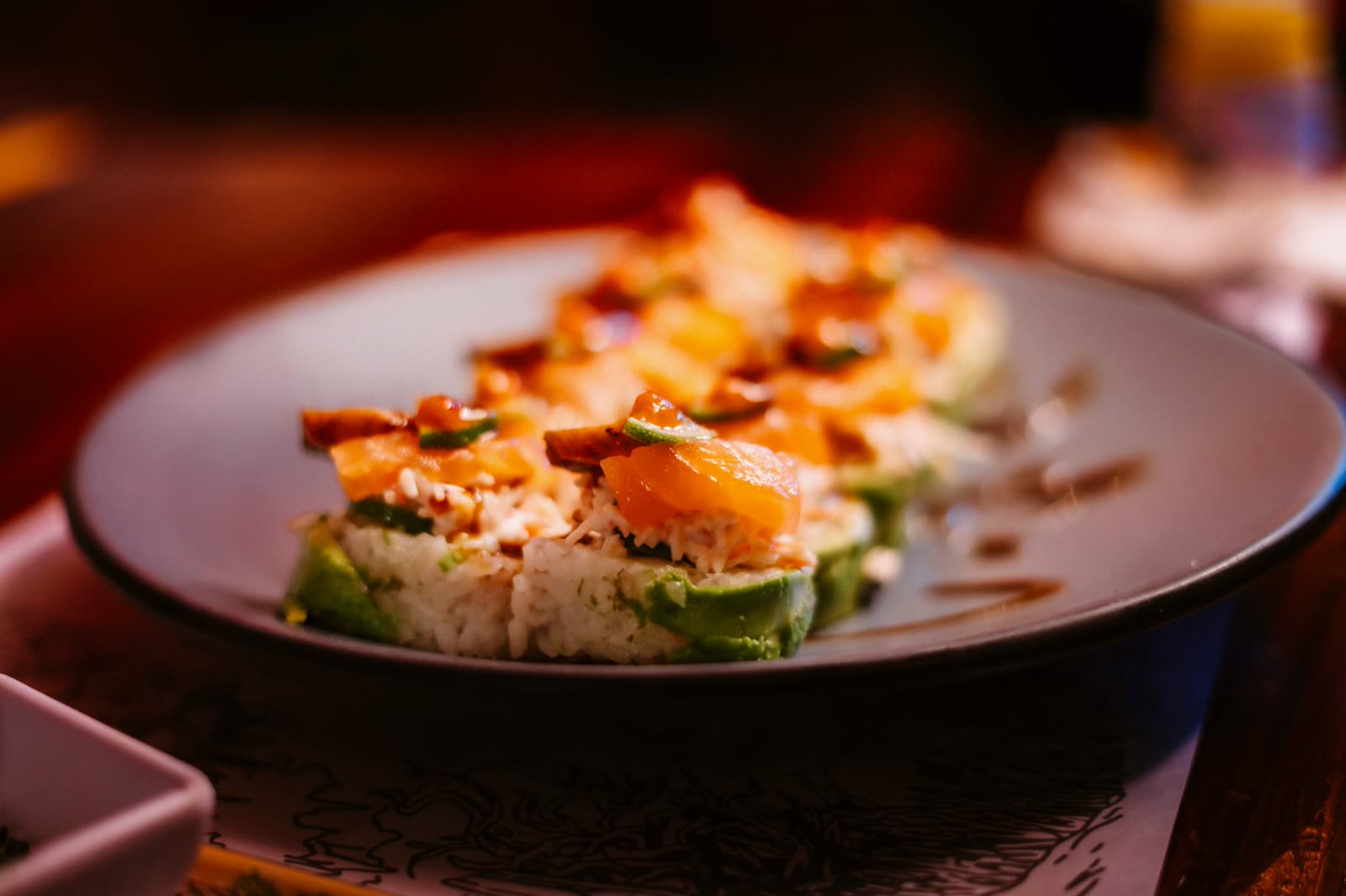 A bowl of salmon, avocado and rice, plated for the table.