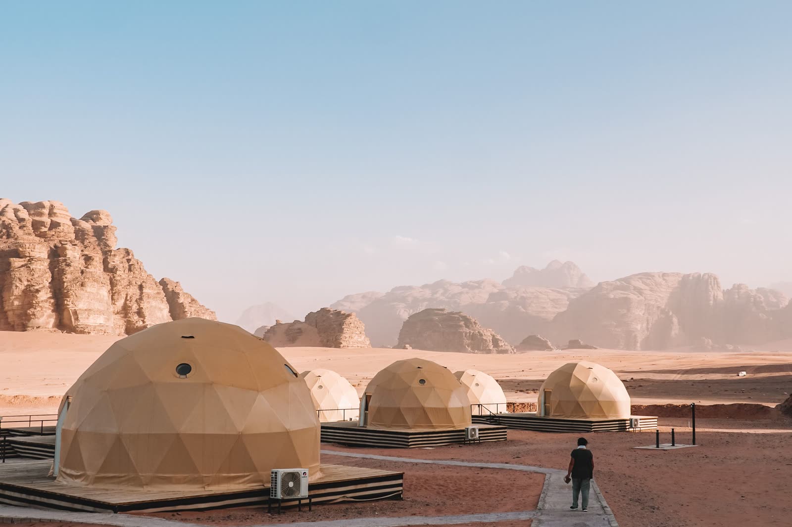 Domed desert tents pitched below the sandstone cliffs of Wadi Rum.