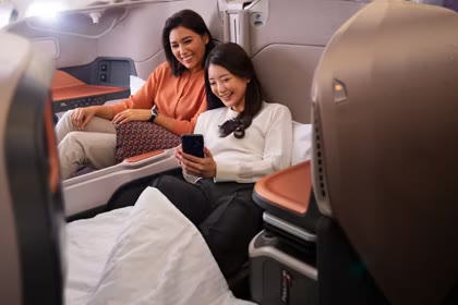 Two travellers relaxing in adjacent business class seats.