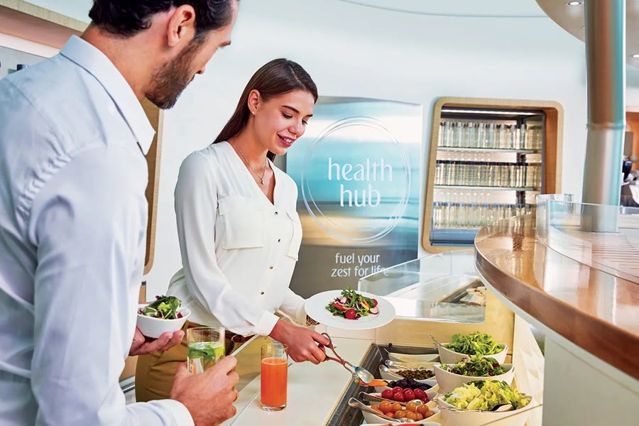 Travellers serving themselves from a lounge buffet of salads and fresh food.